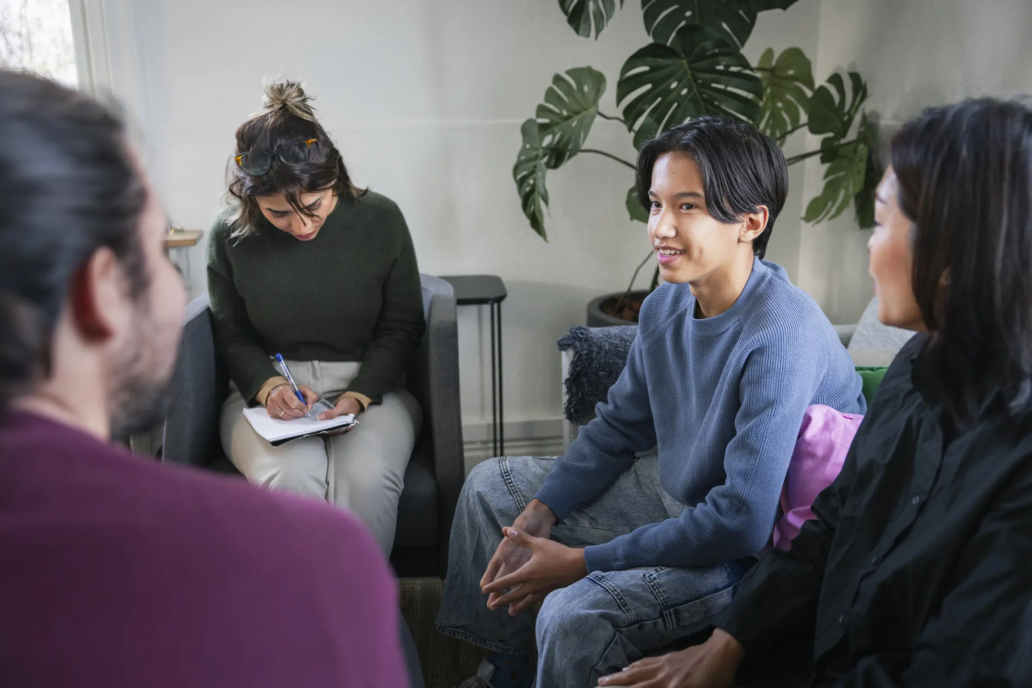 An Asian man smiles while sitting among peers in group therapy.
